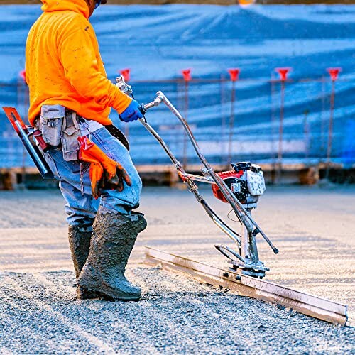 Construction worker leveling concrete with a machine.