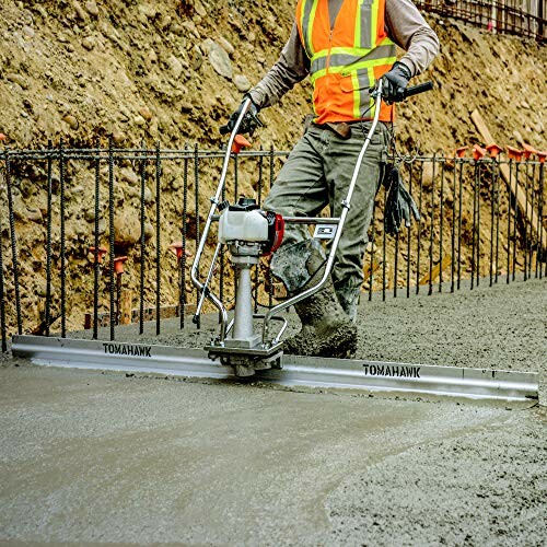 Construction worker using a power screed to level concrete.