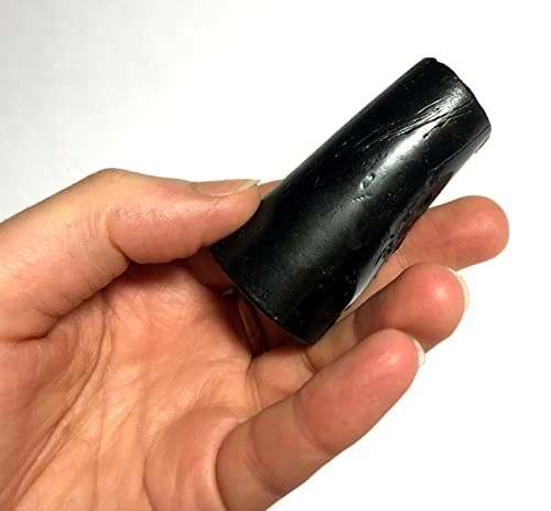 Hand holding a smooth, black, cylindrical object