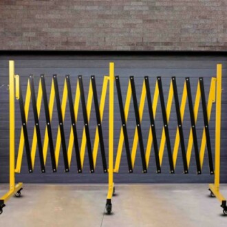 Yellow and black expandable barrier on wheels in front of a wall.